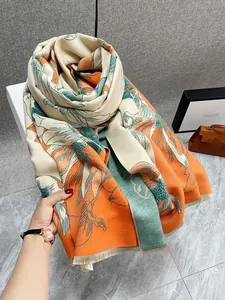 Dettaglio della sciarpa in finto cashmere con motivi floreali e frange beige fini