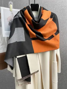 Dettaglio della sciarpa color-block arancione e nera su un cappotto di lana in un set elegante