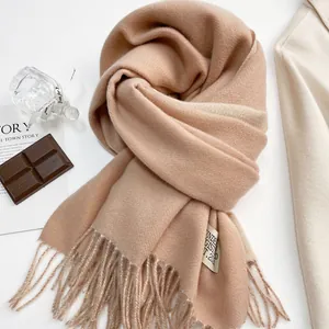 Dettaglio della texture della sciarpa in cashmere cammello con etichetta e frange