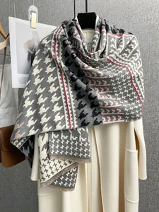 Dettaglio della sciarpa in maglia pied-de-poule con frange su un cappotto beige