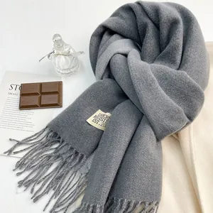 Dettaglio di sciarpa grigio scuro effetto cashmere con lunghe frange ed etichetta tessuta