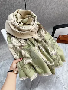 Dettaglio di sciarpa spessa in cashmere con motivi floreali a foglie e frange ai bordi