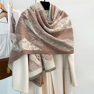 Dettaglio dei motivi a farfalla e rosa su uno scialle reversibile in finto cashmere con nappe