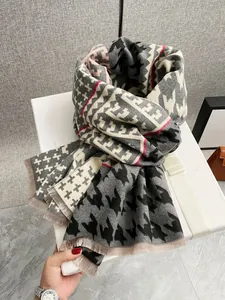 Dettaglio di sciarpa pied de poule simil-cashmere con frange sottili e confezione