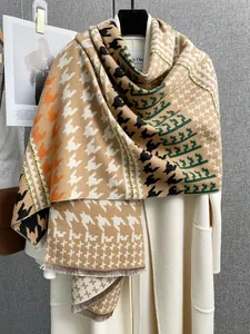Dettaglio dello scialle in cashmere pied-de-poule con frange su cappotto bianco