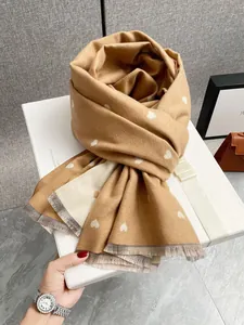 Dettaglio sciarpa in cashmere cammello con cuori bianchi e frange in confezione regalo