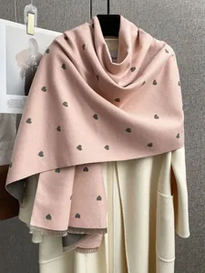 Dettaglio di sciarpa in finto cashmere rosa con motivo a cuori grigi e frange sui bordi