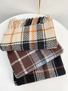 Dettaglio di sciarpe a quadri a strati con frange e morbida consistenza in cashmere