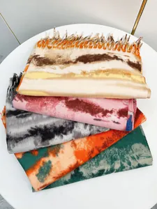 Primo piano di sciarpe tie-dye effetto cashmere con bordi a frange su un tavolo bianco