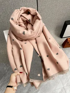 Dettaglio sciarpa reversibile in finto cashmere rosa e grigio con motivo a cuore e frange