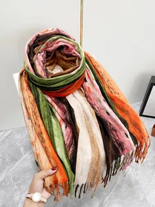 Dettaglio di sciarpa a righe color block con sfumature morbide e finiture con frange