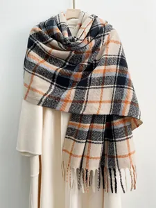 Dettaglio della sciarpa a quadri spessa con lunghe nappe a frange su un cappotto caldo