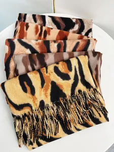 Vista dettagliata di sciarpe in cashmere sintetico con stampa leopardata e frange