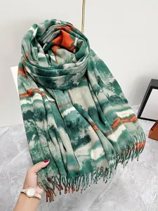 Dettaglio di sciarpa spessa in cashmere tie-dye con motivi verde-arancio e lunghe nappe