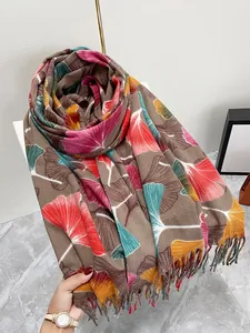 Macro detail of brown scarf with colorful ginkgo leaf patterns and fine tassel fringe