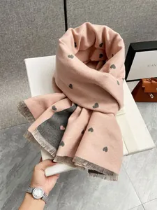 Dettaglio della sciarpa rosa tipo cashmere con motivi a cuore e dettagli di frange
