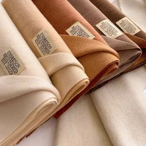Dettaglio di sciarpe pashmina color terra con etichetta e trama fine intrecciata