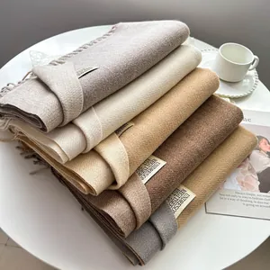 Dettaglio di sciarpe morbide effetto cashmere con frange ed elegante etichetta del marchio