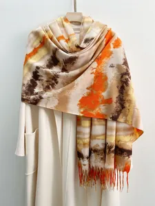 Dettaglio sciarpa sfumata tie-dye con nappe intrecciate a mano su cappotto di lana