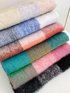 Dettaglio di sciarpe a quadri arcobaleno in morbido mohair con texture pelosa e frange