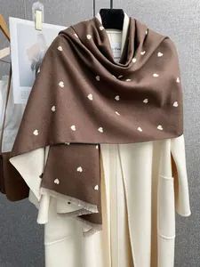 Dettaglio della sciarpa in cashmere marrone caffè con motivo a cuori e nappe eleganti
