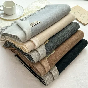 Dettaglio di morbide sciarpe effetto cashmere multicolore con frange ed etichetta logo