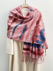 Dettaglio della sciarpa tie-dye tipo cashmere con frange su appendino in legno