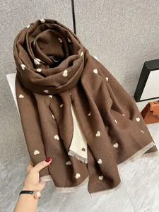 Dettaglio della sciarpa morbida marrone effetto cashmere con cuori bianchi e frange