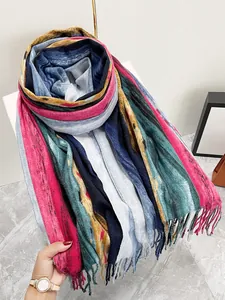 Dettaglio della trama di una sciarpa a maglia a righe con lunghe nappe colorate