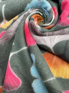 Close-up of soft tassel scarf featuring a vibrant maple leaf print and plush texture