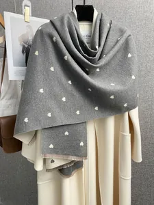 Dettaglio sciarpa grigia tipo cashmere con motivi a cuore e delicate frange