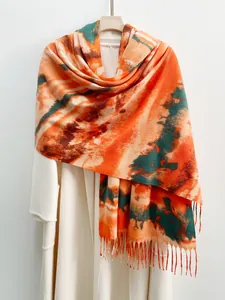 Dettaglio della sciarpa in cashmere tie-dye con frange arancioni e texture sfumata
