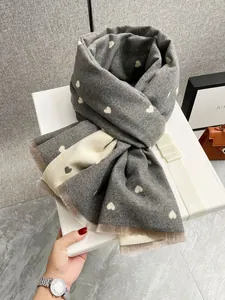 Dettaglio del motivo a cuore e frange morbide sulla sciarpa di cashmere in scatola regalo