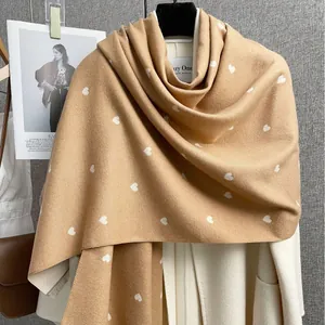 Sciarpa invernale marrone con cuori bianchi drappeggiata su un cappotto bianco
