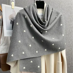 Sciarpa grigia effetto cashmere con cuori abbinata a un cappotto beige per l'inverno