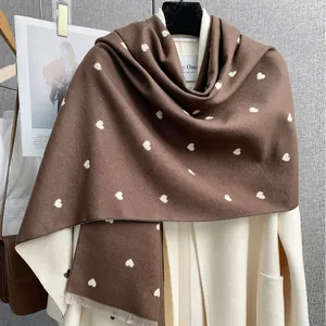 Sciarpa invernale marrone con cuori bianchi e frange su cappotto di lana bianco
