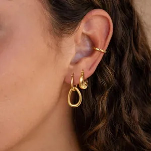 Polished gold plated brass earring set featuring zircon accents on a female model