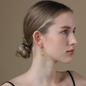 Elegant gold plated hollow teardrop earrings with crystals worn by a model