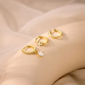 Detailed view of gold plated brass earrings set with zircon stones on silk fabric