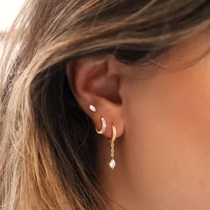 Detail of gold-plated brass hoop earrings and marquise zircon studs set on model