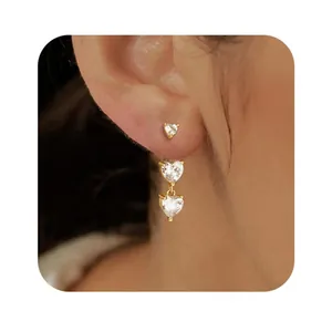 Detail of elegant gold heart-shaped stud earrings with sparkling white zircons on model