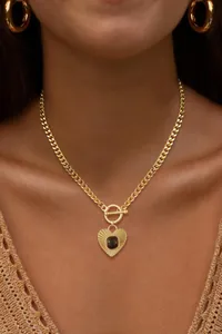 Detail of vintage heart pendant with sunburst texture and gemstone on a gold OT buckle chain