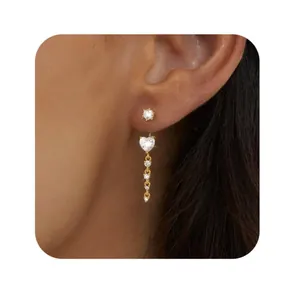 Close-up of golden heart tassel earrings with zircon studs worn by a model