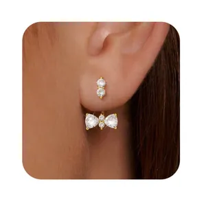 Detailed close-up of a zircon bow earring with gold finish on a model's ear