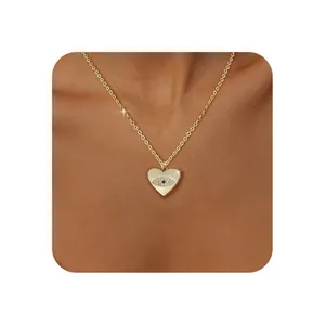 Detail of gold heart pendant necklace featuring evil eye design with blue gemstone inlay