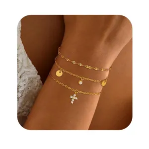 Détail du bracelet triple couche doré avec pendentif croix porté au poignet d'une femme