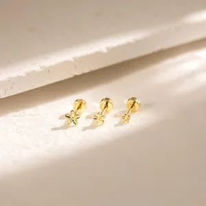 Detailed close-up of three graded gold floral studs on a minimalist textured surface