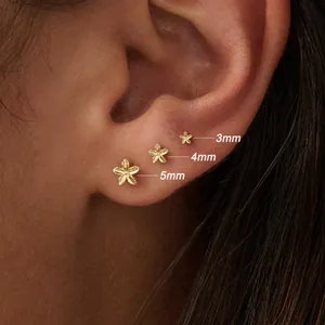 Detailed view of three sizes 3mm 4mm 5mm gold plated flower stud earrings on ear