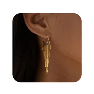 Close-up of elegant gold tassel earrings with cascading fine chains worn by a model