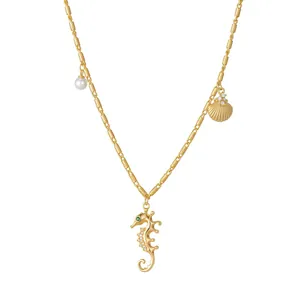 Collier doré avec perle, coquillage et pendentif hippocampe avec œil en pierre verte